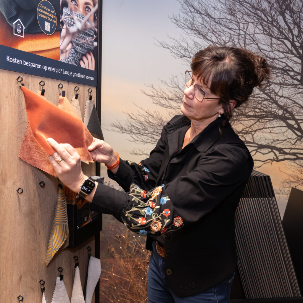 Ingrid met gordijnstoffen in de winkel.